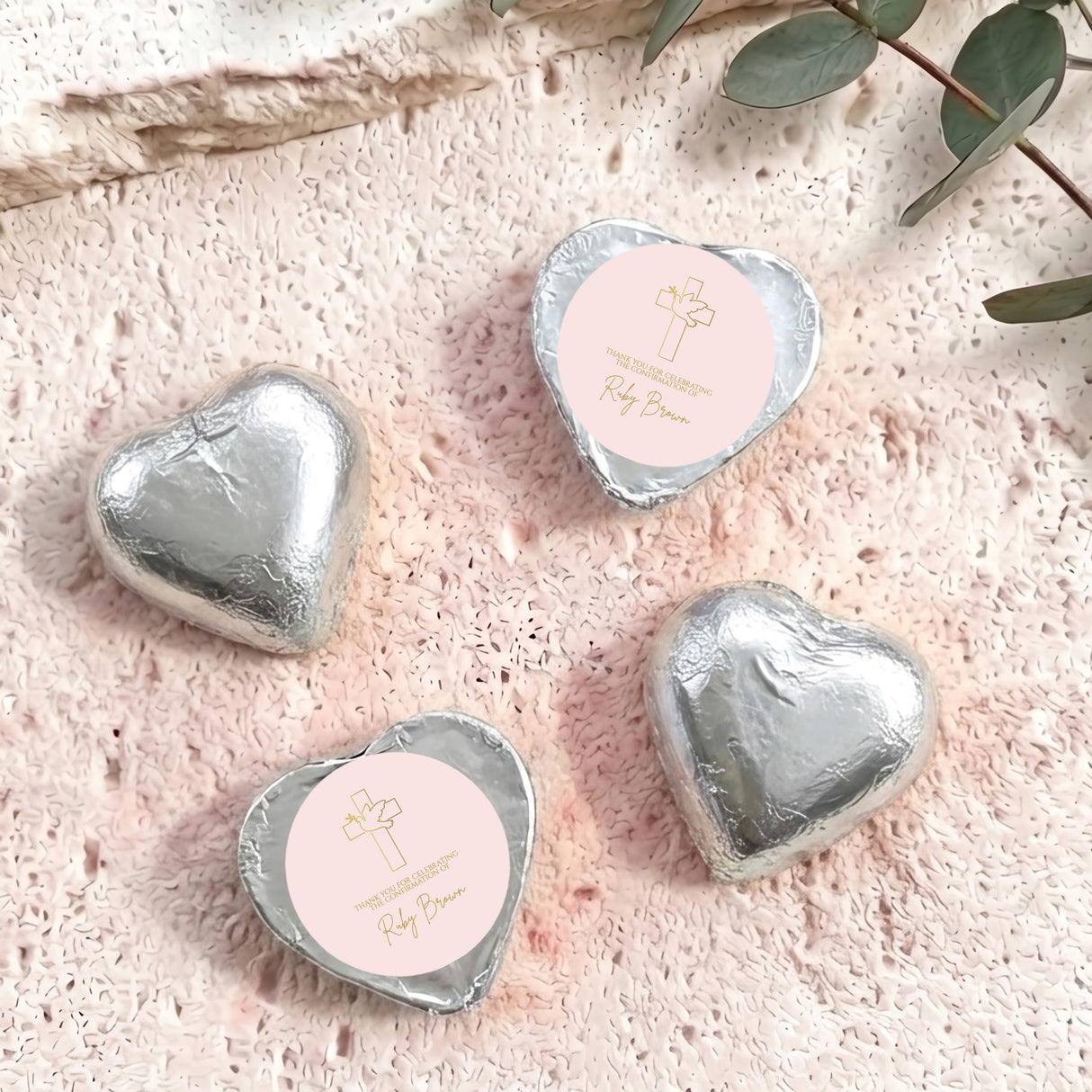 Silver foil-covered chocolate hearts with cross logo on white label