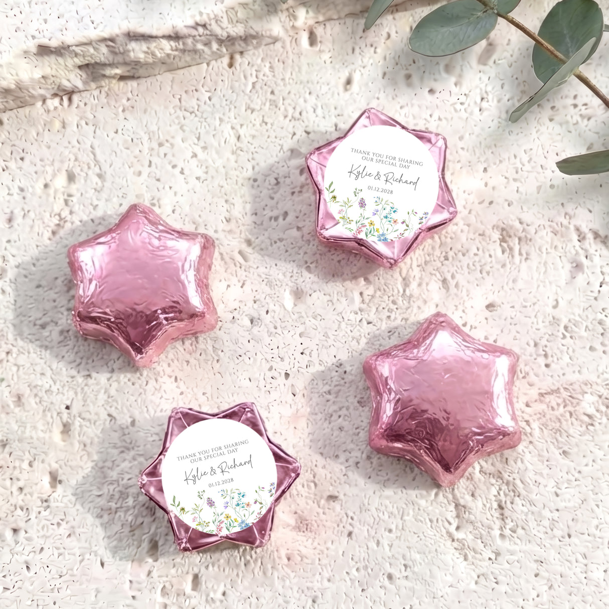 Pink foil-covered chocolate stars with a round printed label and floral accents