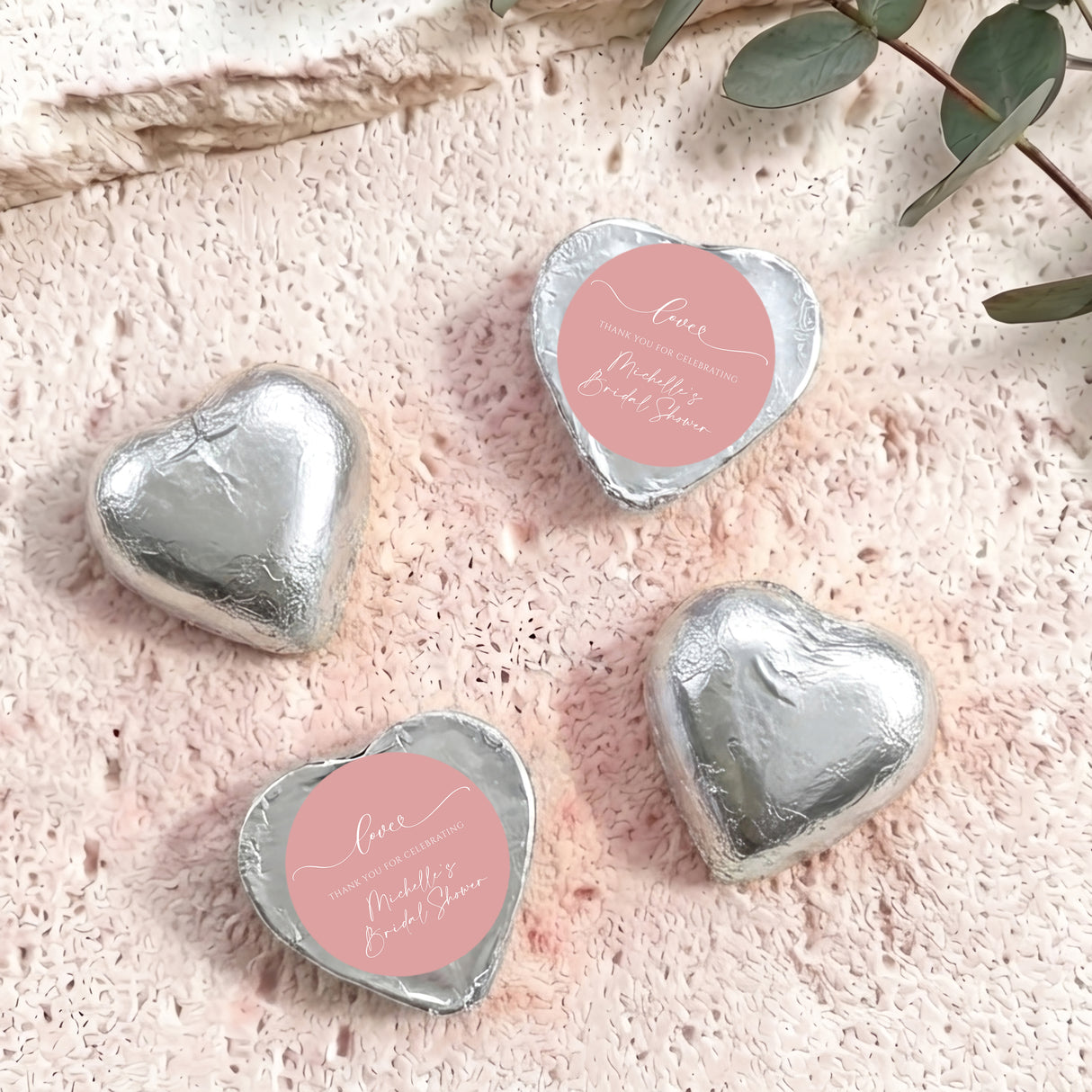 Silver heart-shaped foil-covered chocolates with a round pink label on top