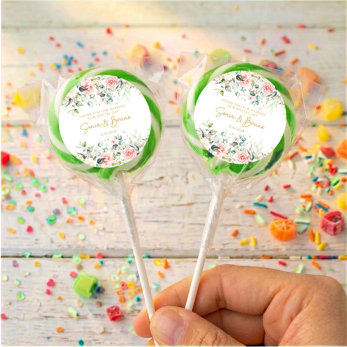 Personalized wedding lollipops with green-bordered round labels, held in hand