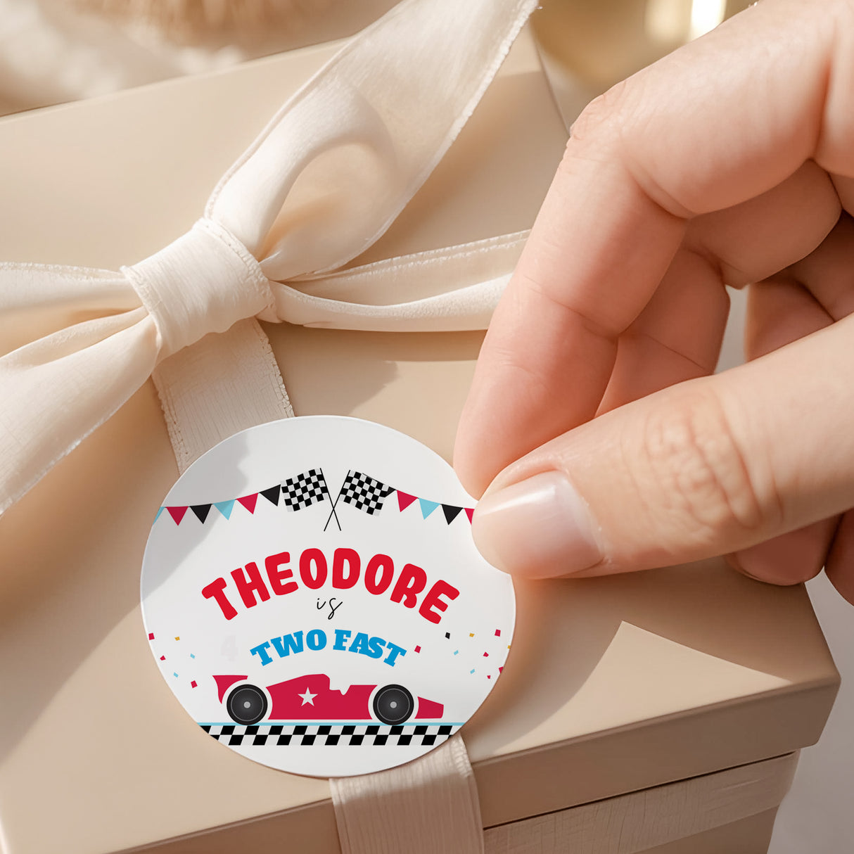 Round race car printed label with checkered flags and text “THEODORE is TWO FAST”