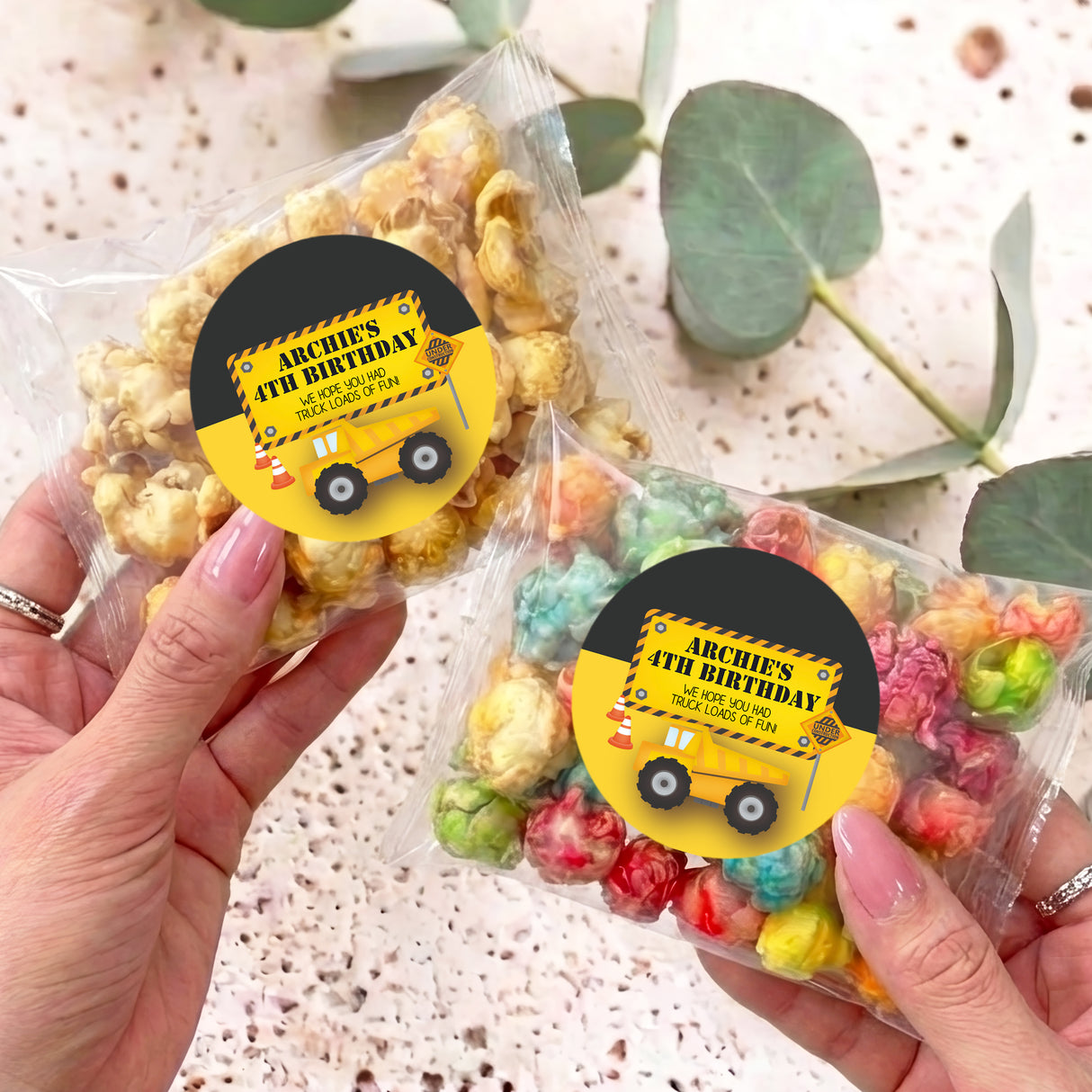 Personalised popcorn bag set with yellow birthday sticker, held in hands