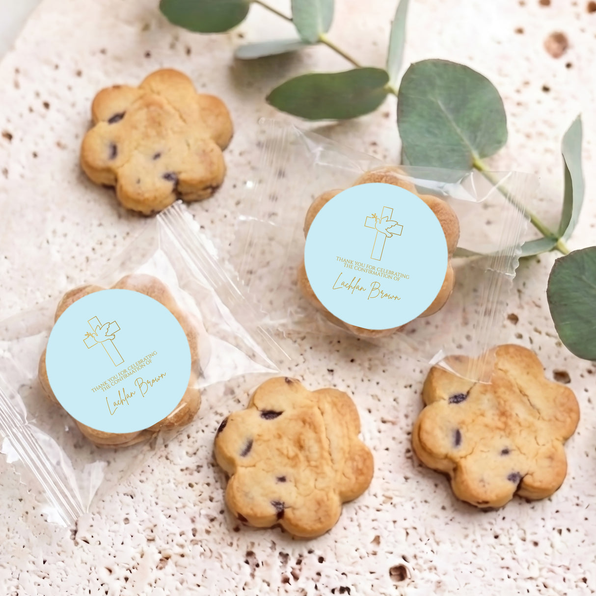 Bite-size chocolate chip cookies with two blue personalised stickers on clear bags