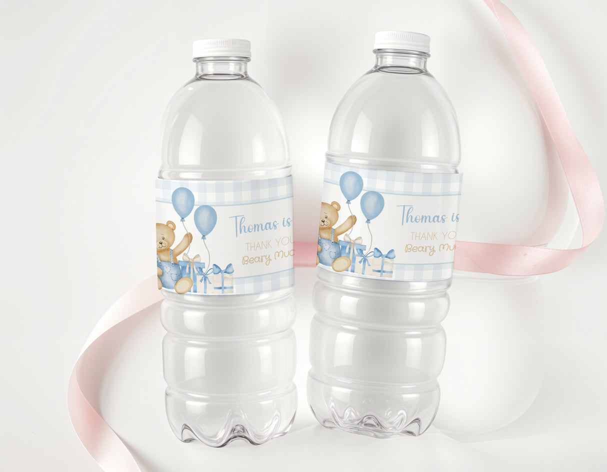 Two clear plastic water bottles with blue teddy bear birthday labels and balloons