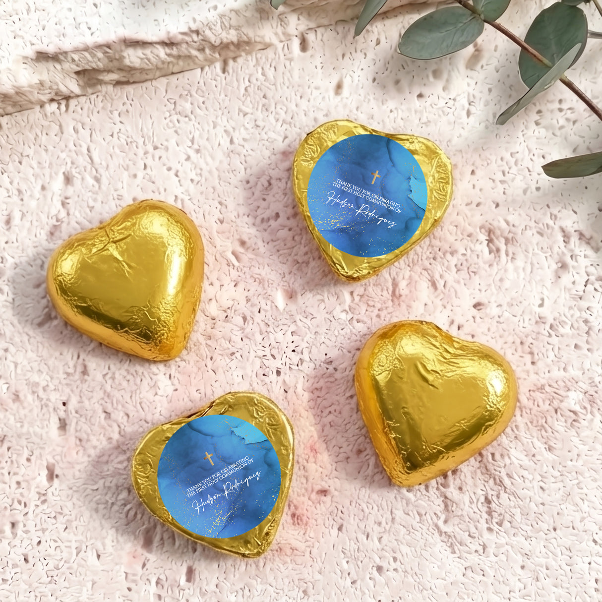 Foil-covered chocolate hearts with gold wrappers, blue center, and gold cross