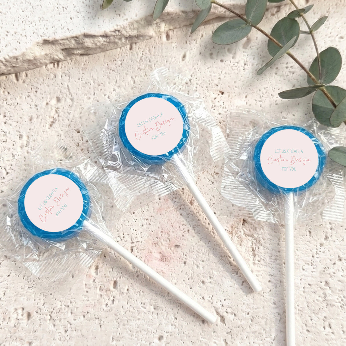 Mini lollipops with blue lollipop tops, wrapped in clear plastic on white sticks.