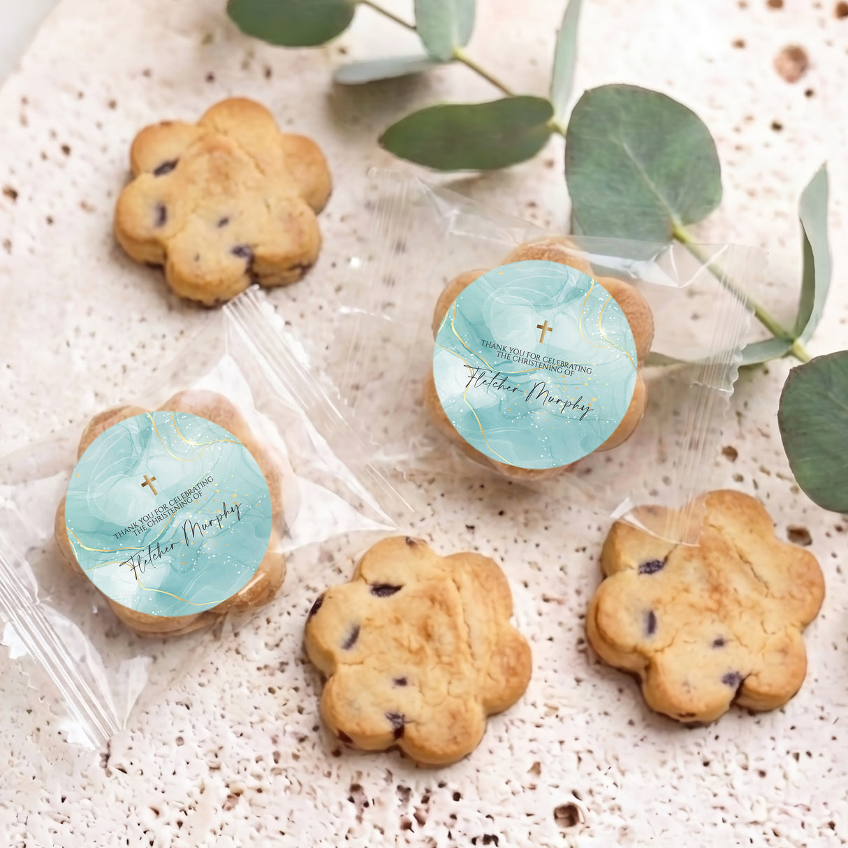 Bite-size choc chip cookies in clear bags with blue round labels and gold cross