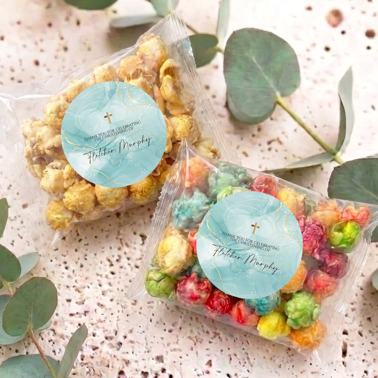 Personalised popcorn bag with blue round label and multicolour popcorn, lying flat.