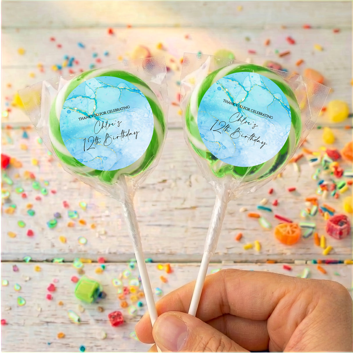 Kids birthday personalised lollipops with blue marble design and green accents, on lollipop sticks