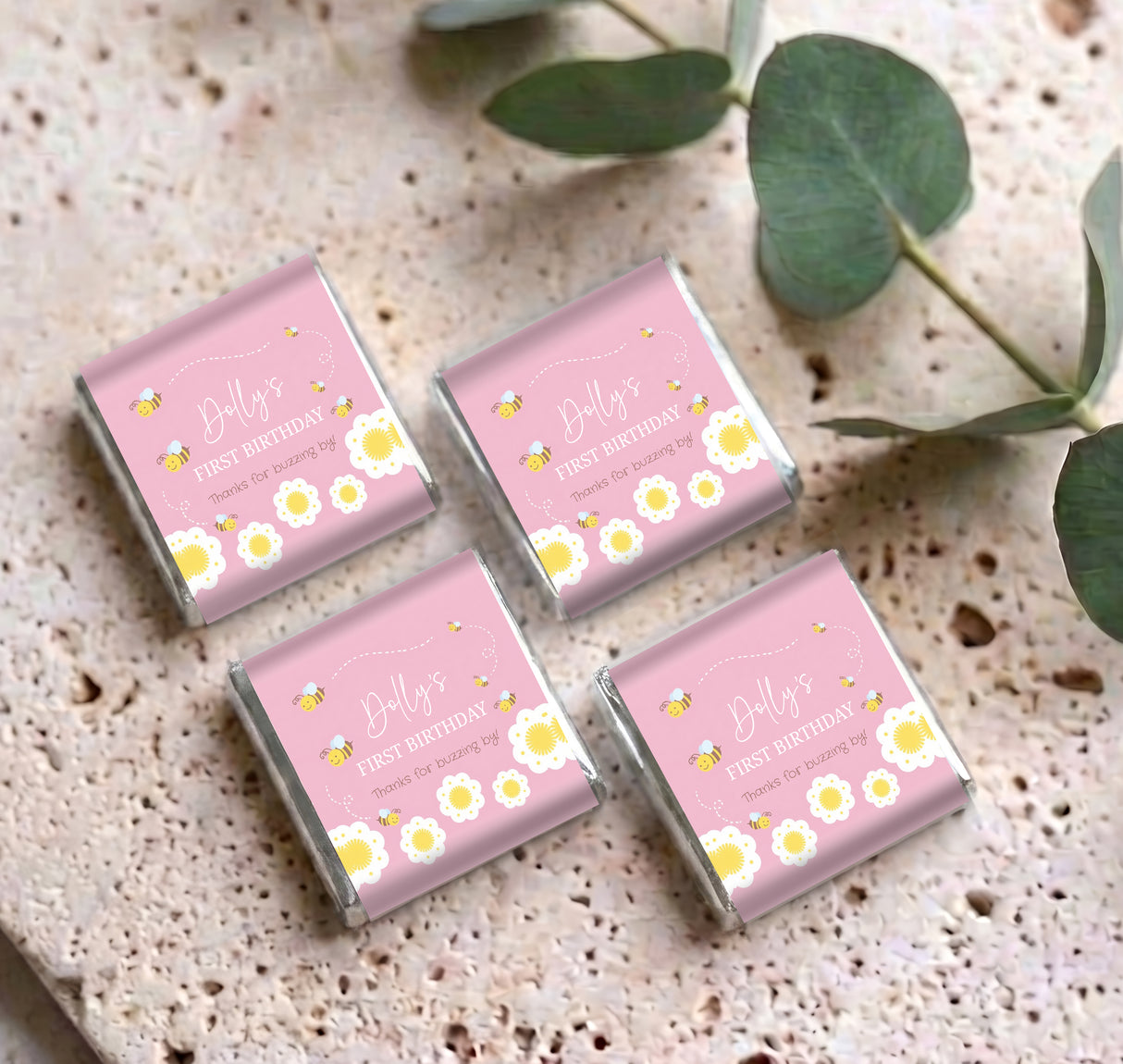 Four pink mini chocolate boxes with bee and floral “First Birthday” design, arranged