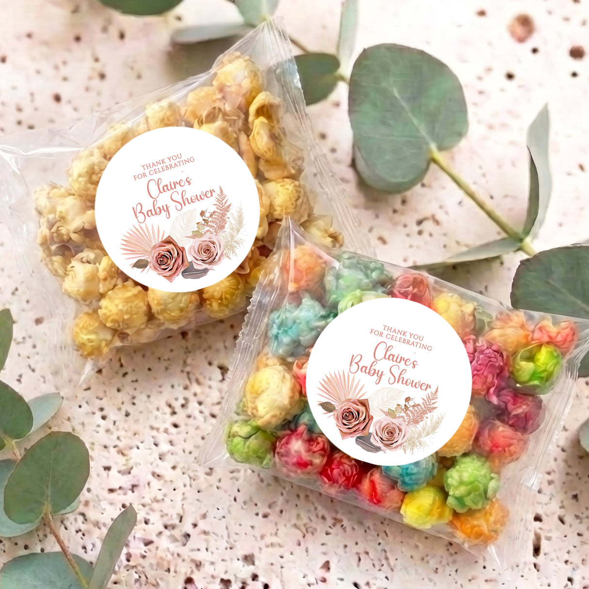 Two clear popcorn bags with multicolor sweets and circular floral 'Baby Shower' sticker