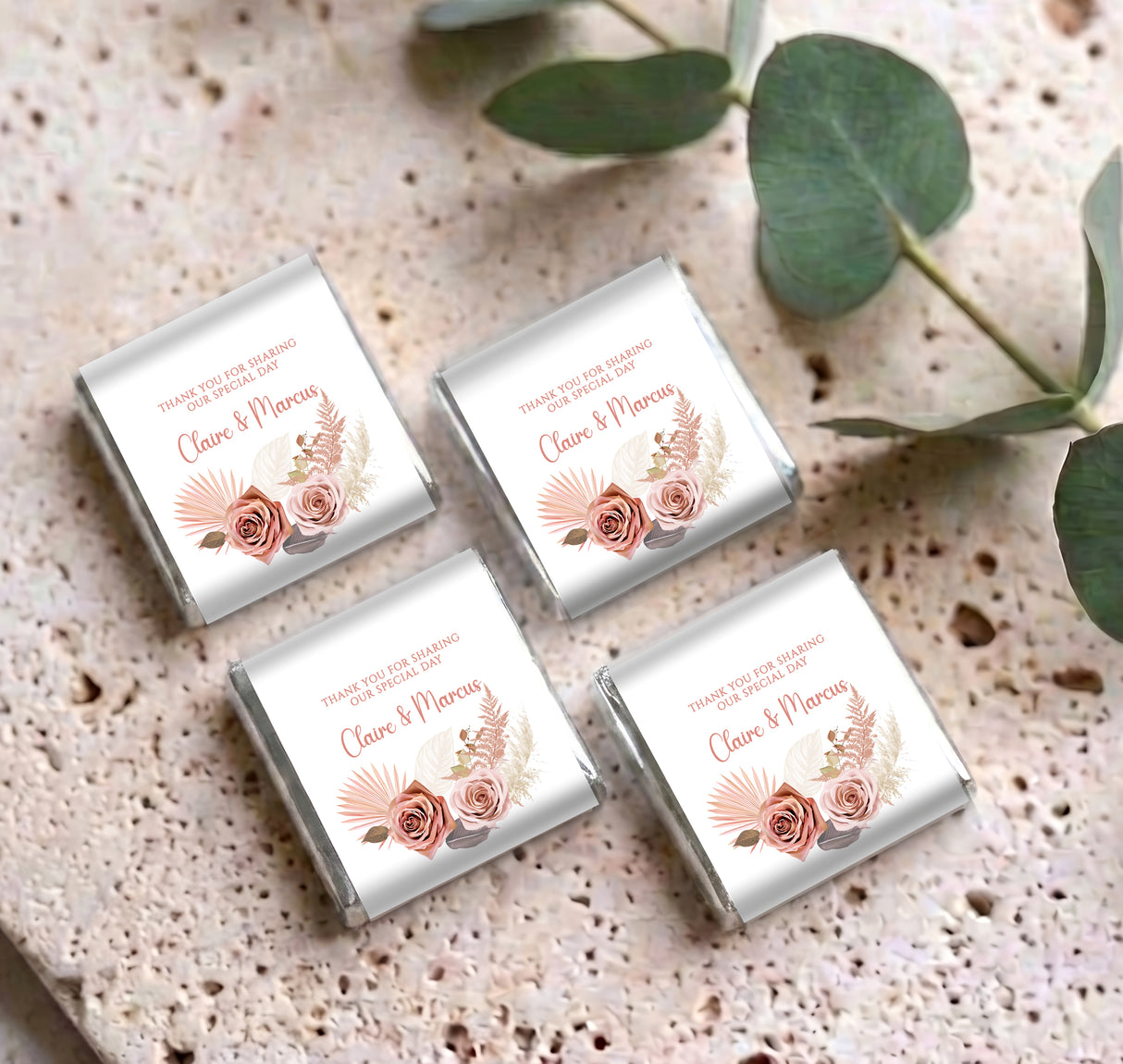 Four mini personalised chocolate wrappers with pink rose floral labels on a textured surface.