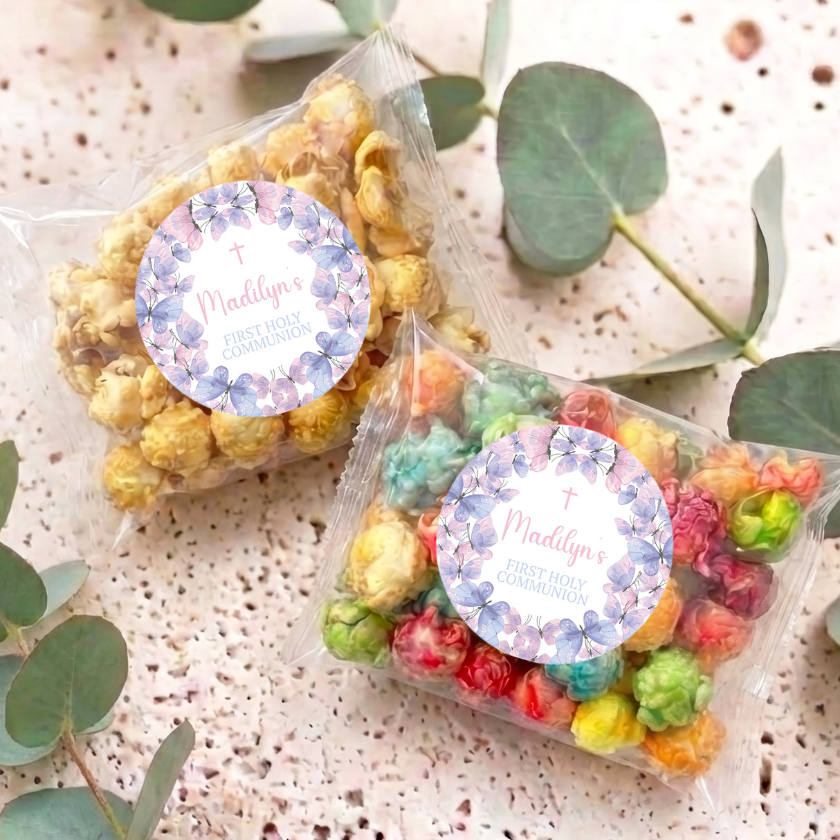 Two personalised popcorn bags with clear wrap, colorful popcorn, round purple butterfly labels