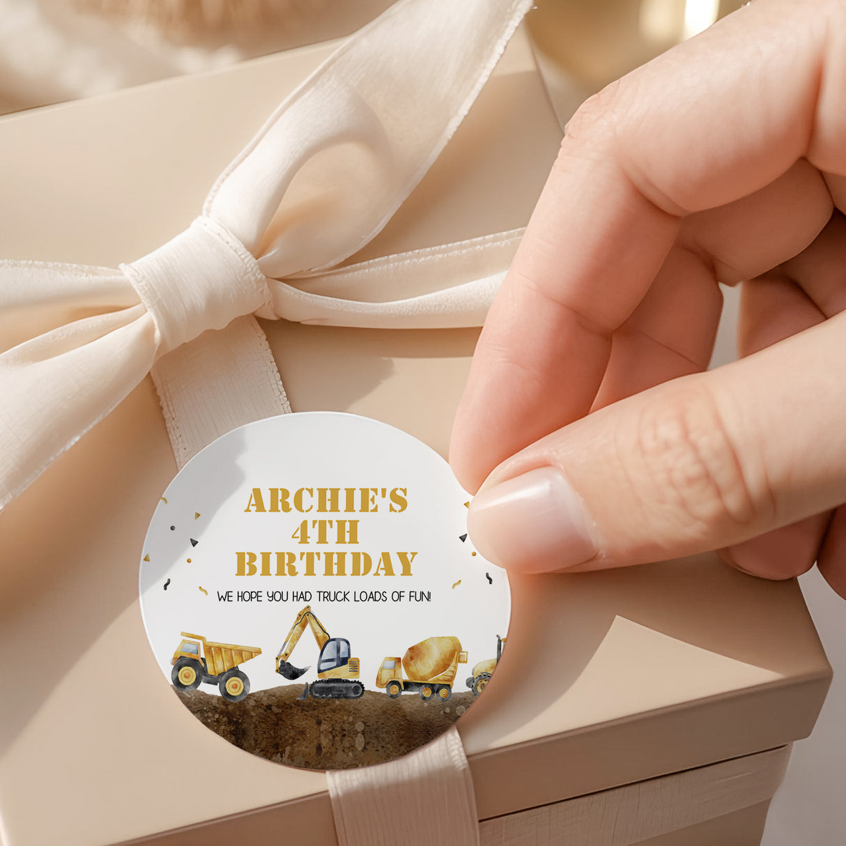 Round construction truck birthday label with “ARCHIE’S 4TH BIRTHDAY” text