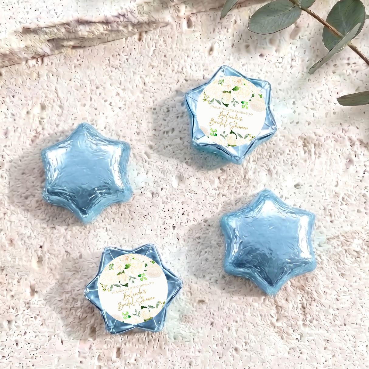 Foil-covered chocolate stars in light blue with a printed floral label on one star.
