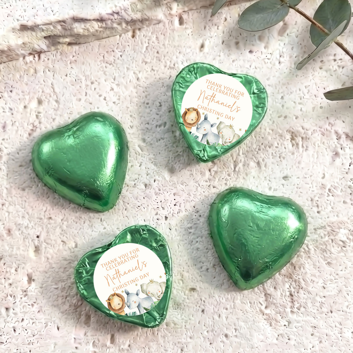 Green foil-covered chocolate heart with round Christening label and baby animals