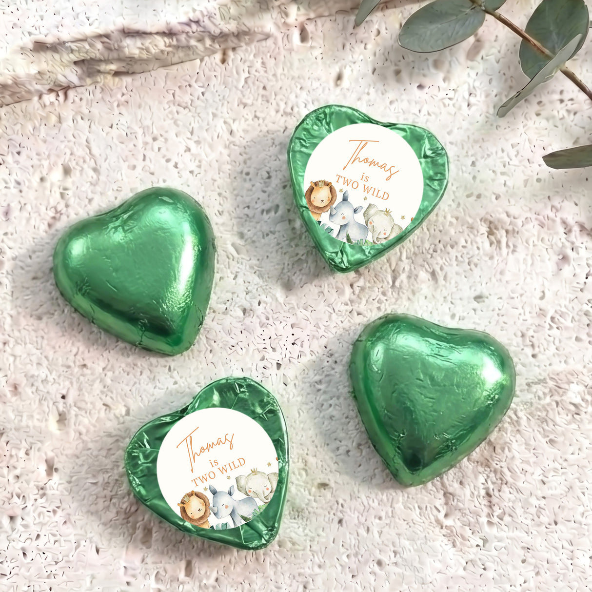 Green foil-covered chocolate hearts with small personalized center labels and embossed shiny surface