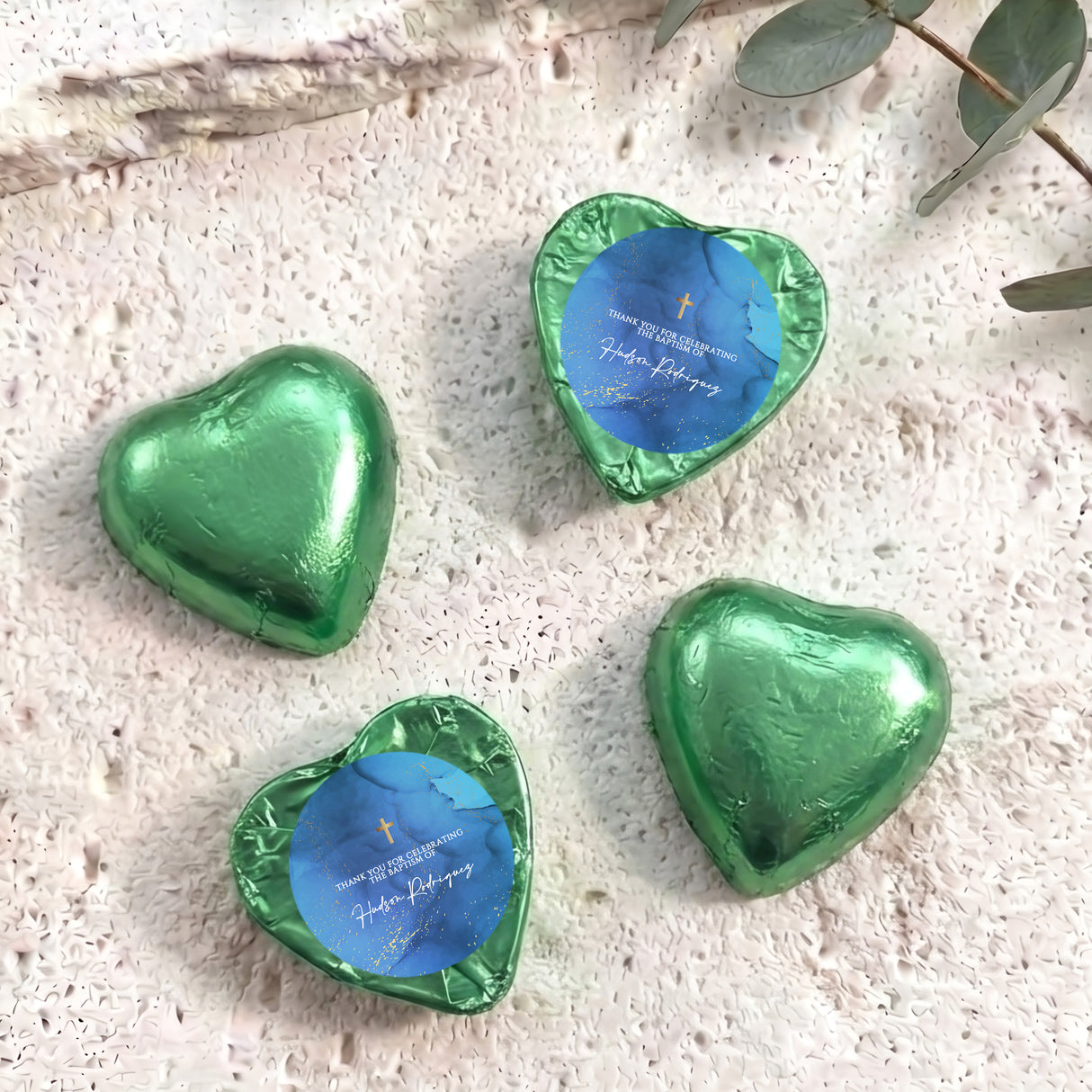 Green foil-covered chocolate heart favors with gold cross and blue personalized label