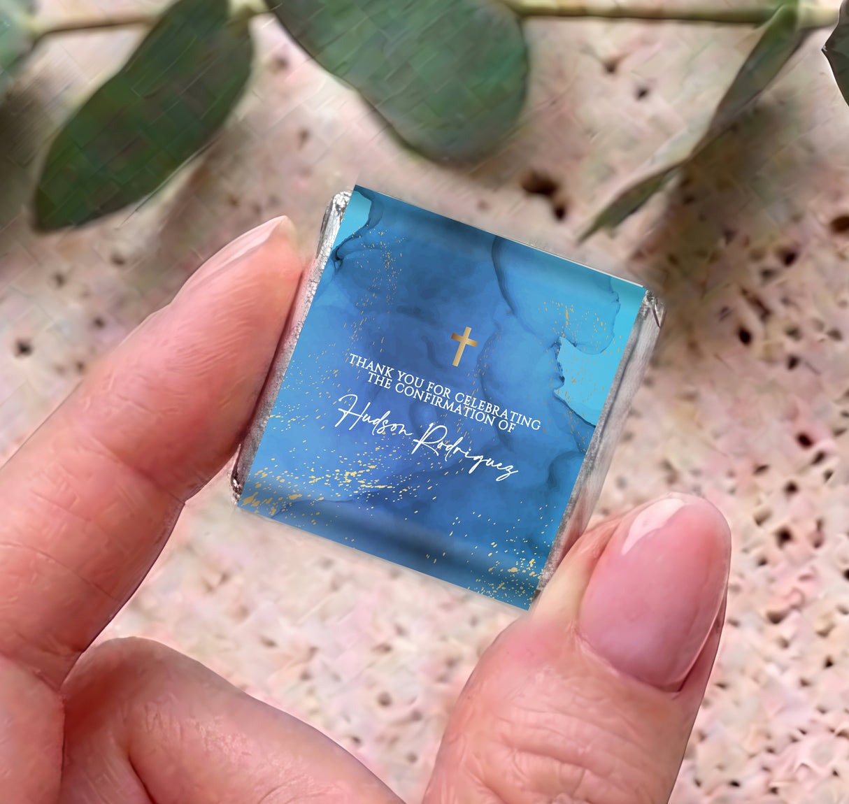 Close-up blue mini chocolate wrapper with gold cross and printed confirmation text