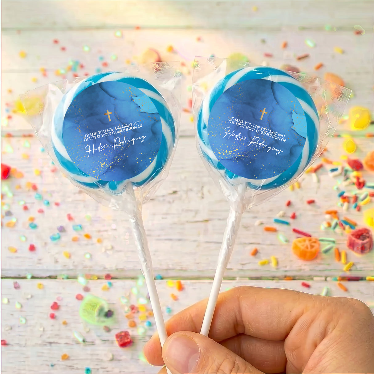 Personalised lollipops with deep blue round labels, gold cross, clear wrappers, white sticks
