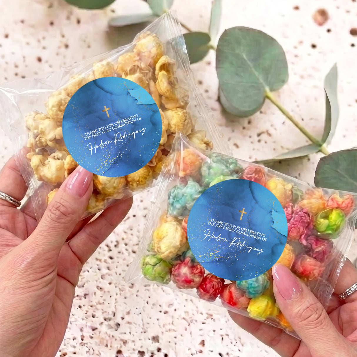 Personalised popcorn bag with clear wrapper and blue round tag with gold cross