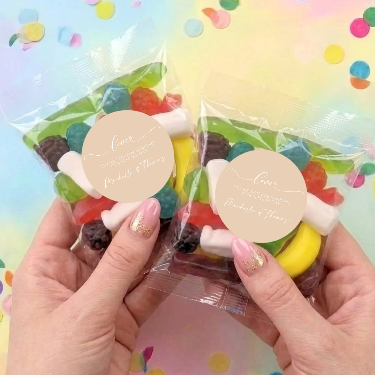 Two personalised clear lolly bags held in hands, assorted fruit sweets and beige love labels
