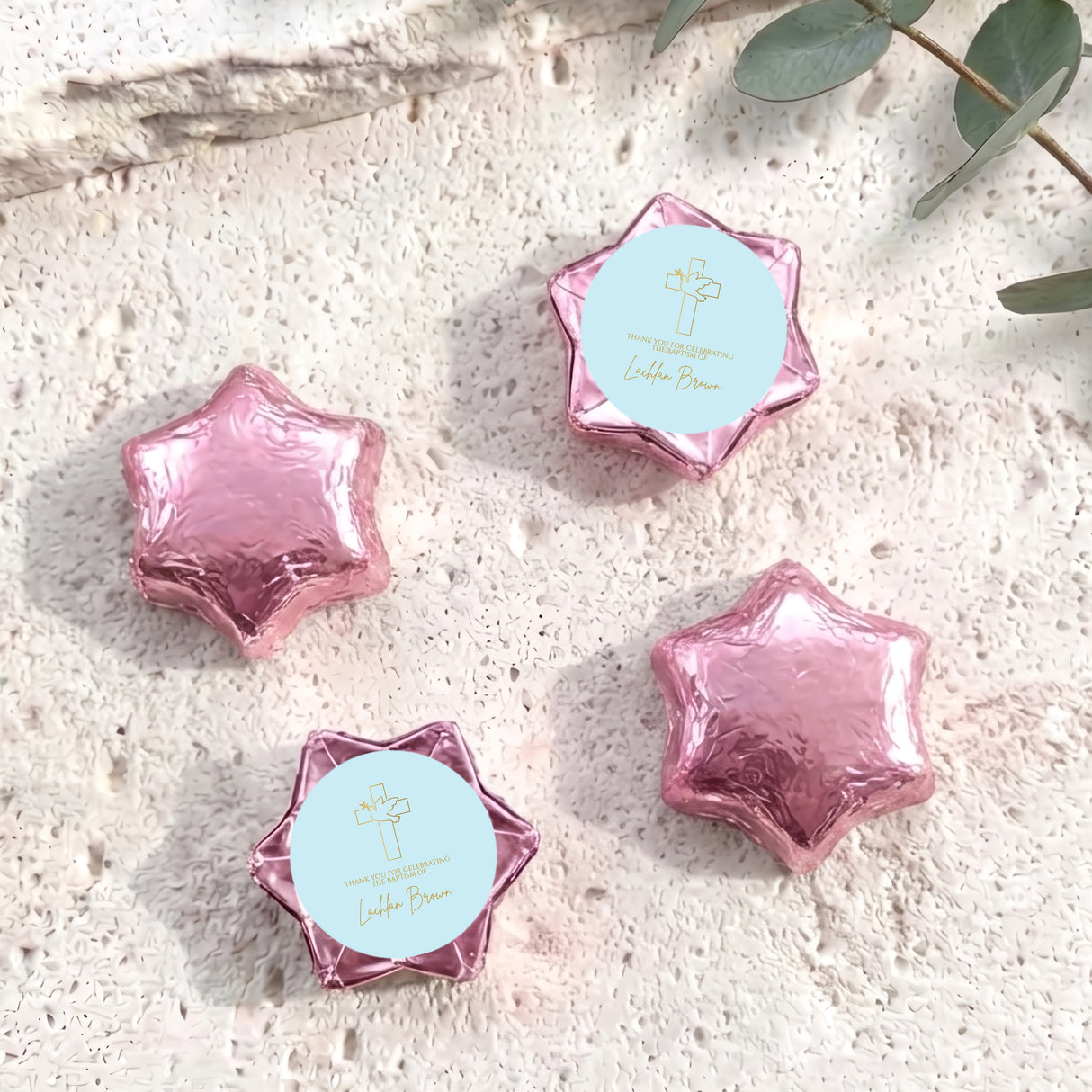 Pink foil-covered chocolate stars with cross and name card on wrappers