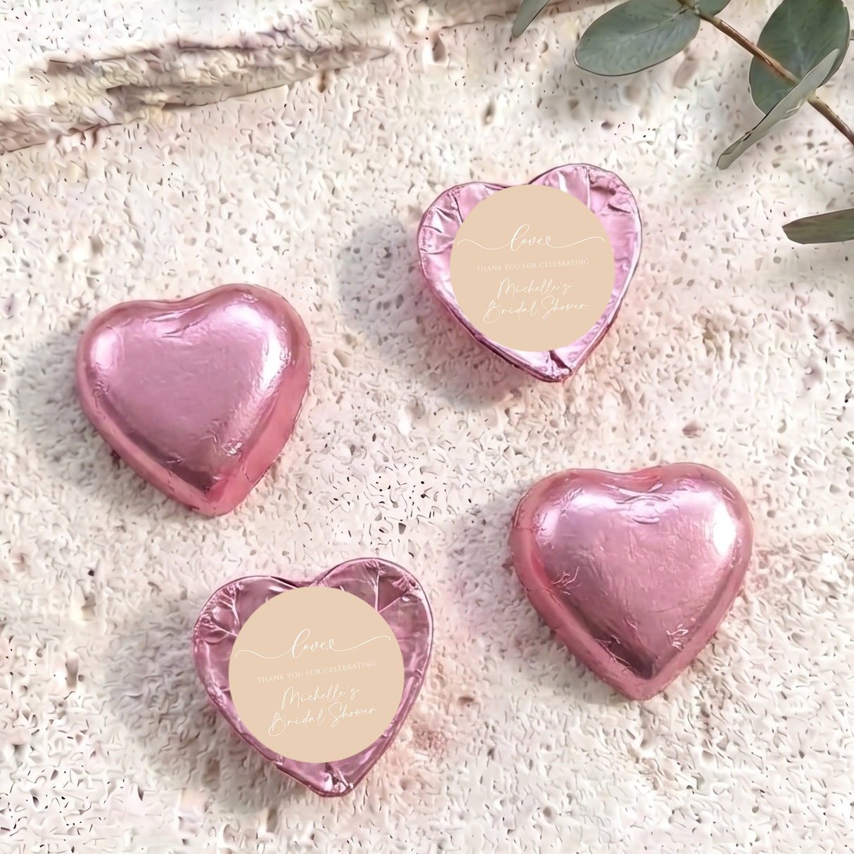 Pink foil-covered chocolate hearts with beige round labels and heart shapes