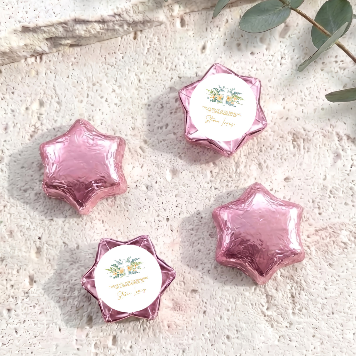 Pink foil-covered chocolate stars with personalised circular cross label on the foil wrapper