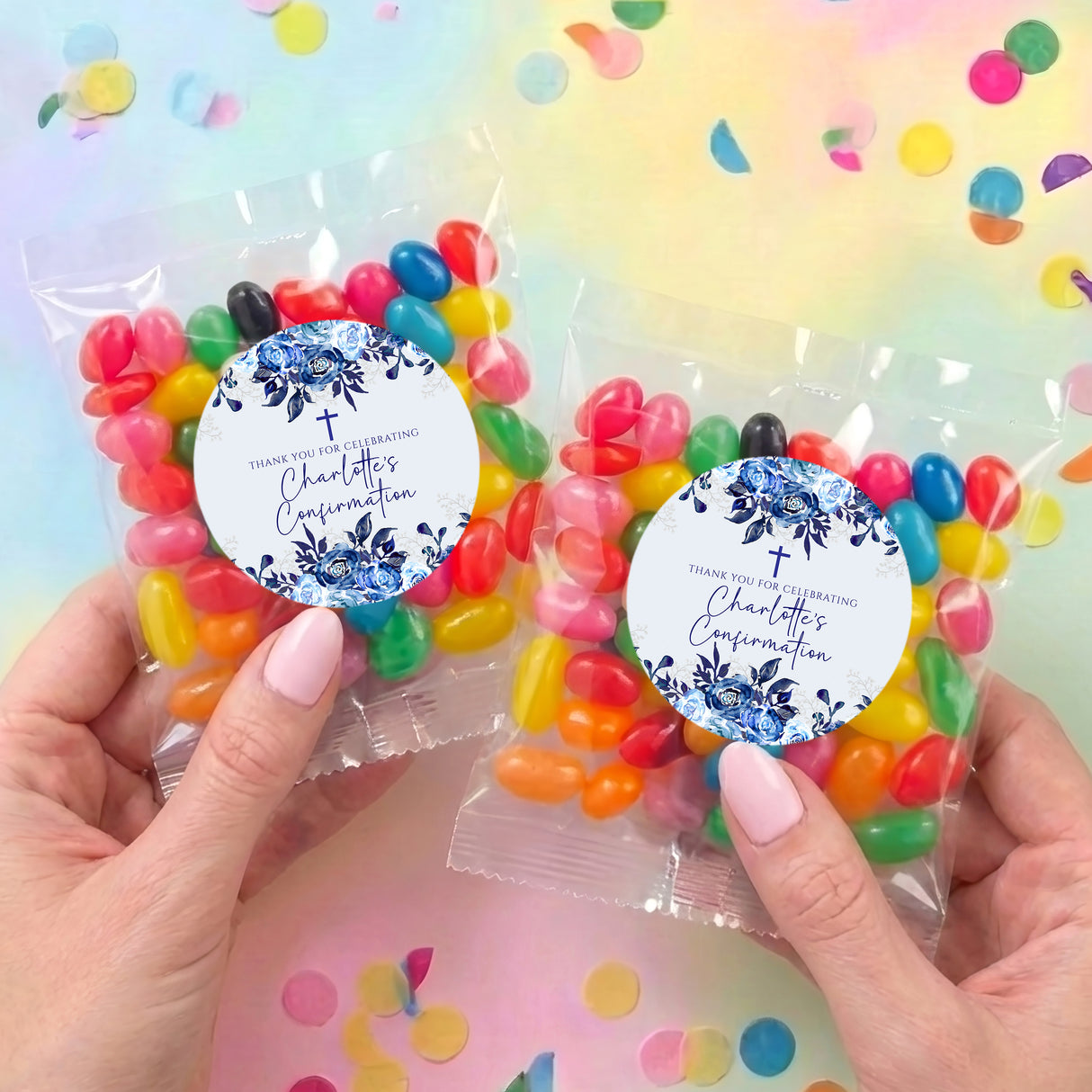 Jelly bean favor bags held in hands, each with round navy floral sticker and colorful beans