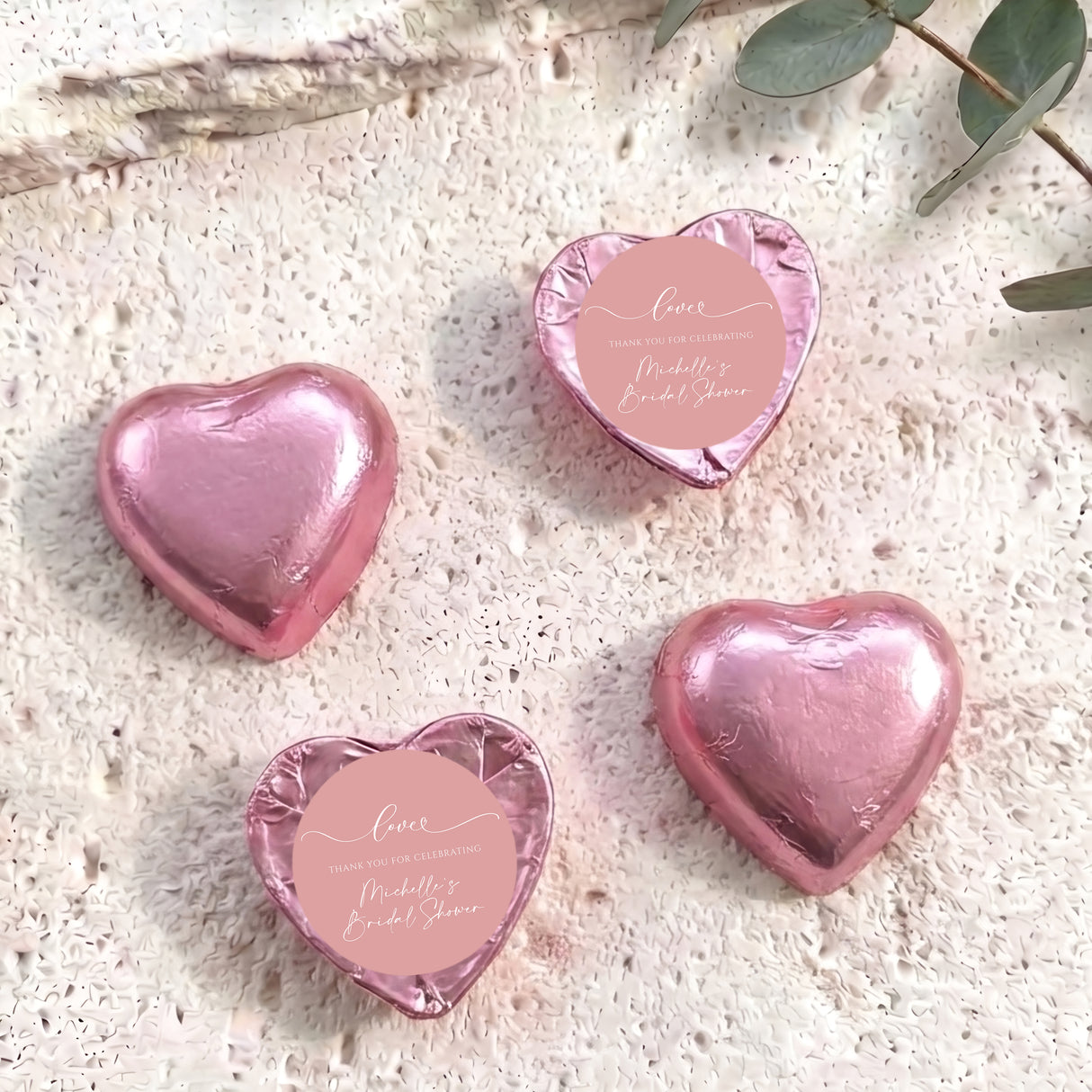 Dusty pink heart-shaped foil-covered chocolates with a round pink label on top
