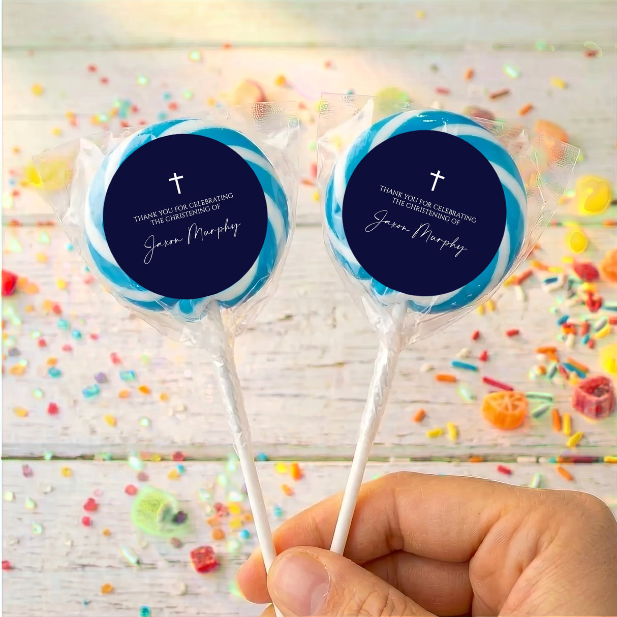 Personalized lollipops with navy round labels, white cross, in clear wrappers.