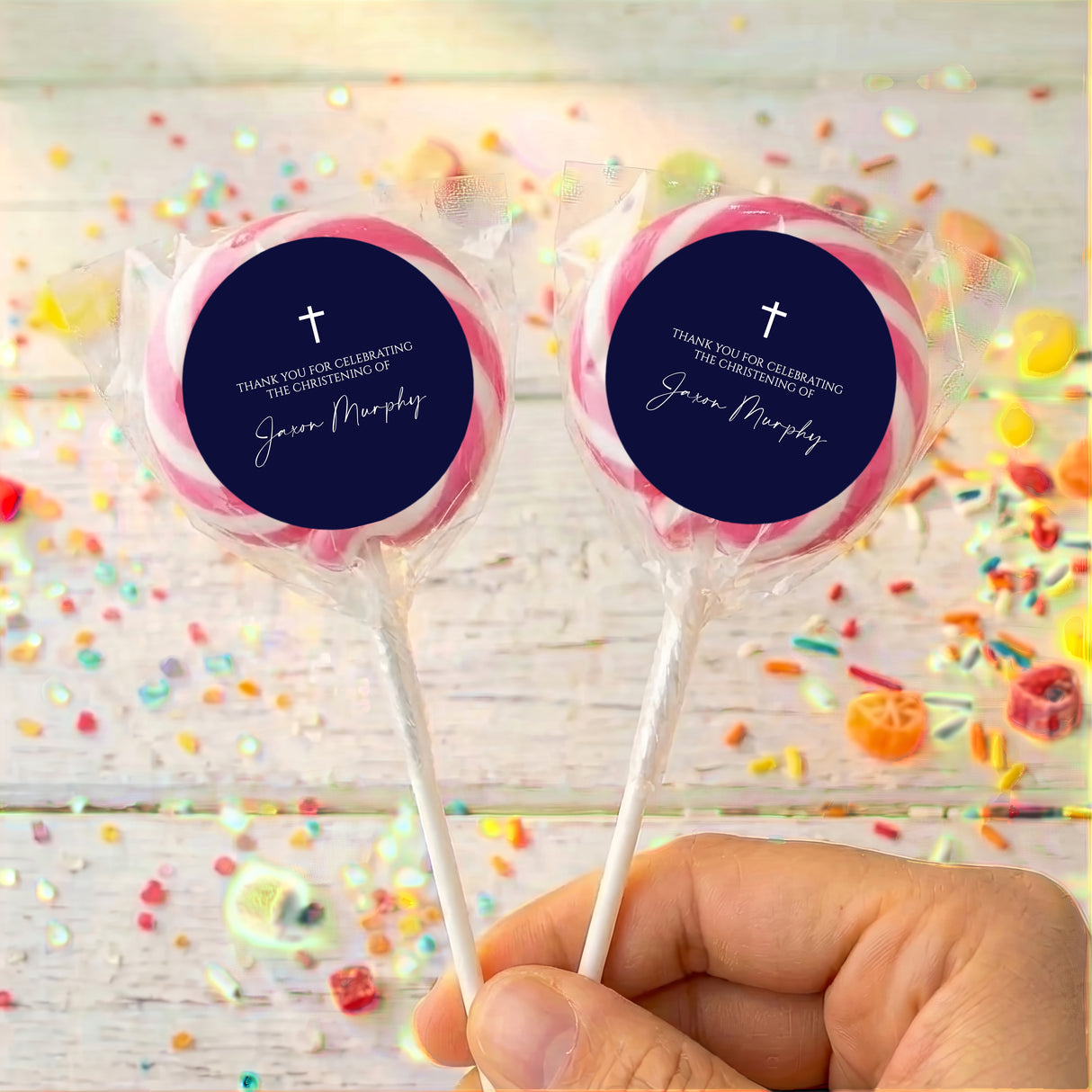 Personalized lollipops with navy round labels, white cross, in clear wrappers.