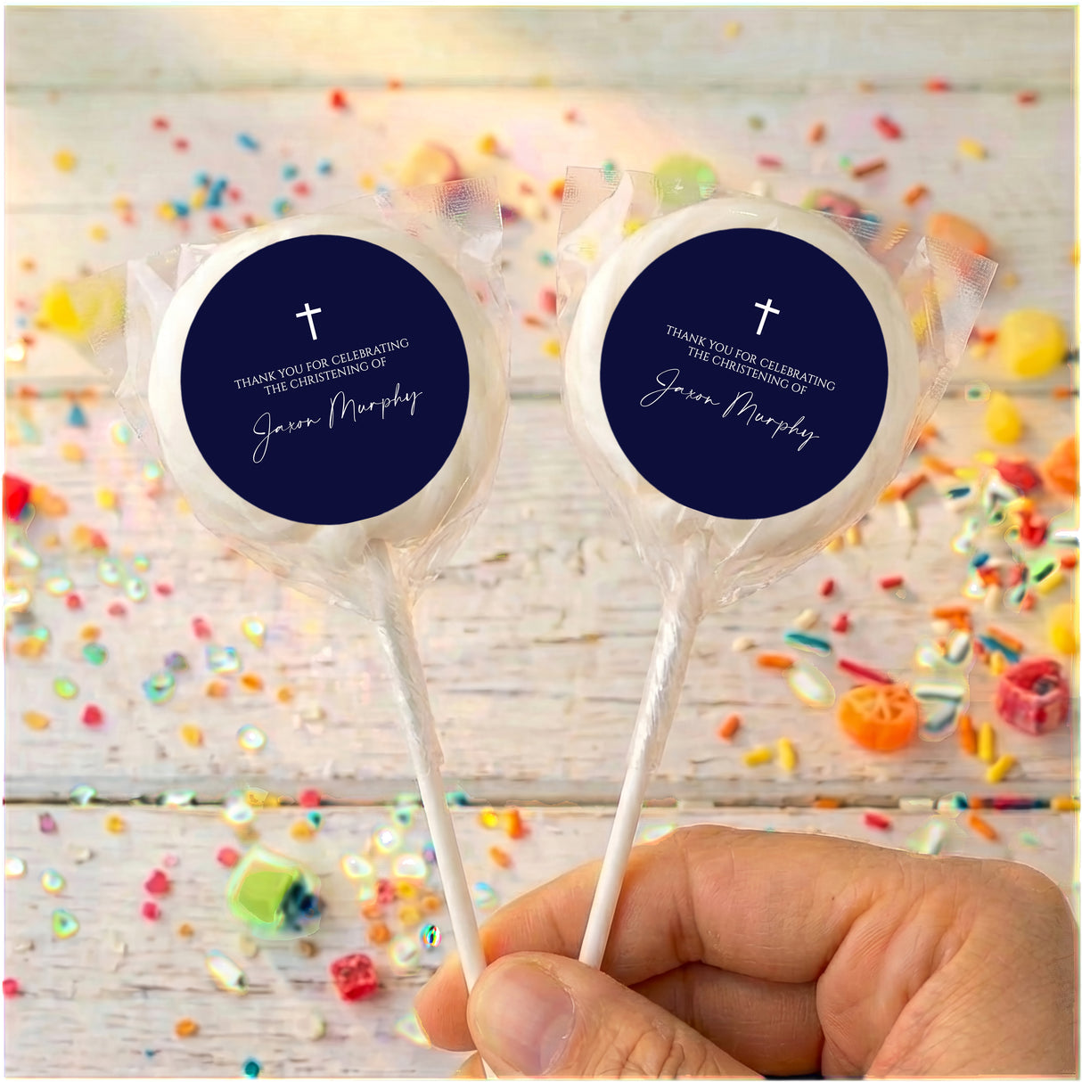 Personalized lollipops with navy round labels, white cross, in clear wrappers.