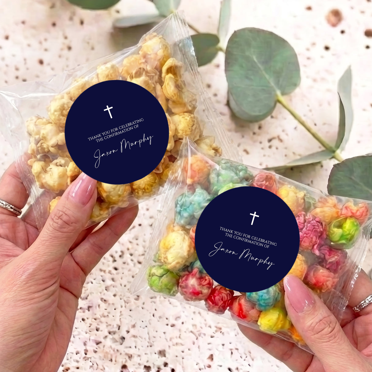 First Communion popcorn bag with navy label and white cross, held in hands