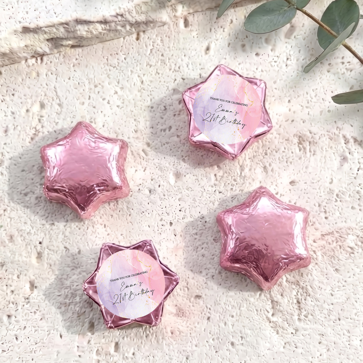 Pink foil-covered chocolate stars with personalized round label in a clear star frame