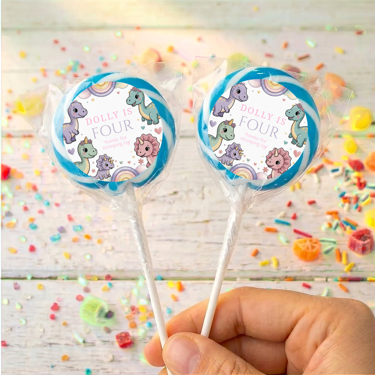 Blue-rim dinosaur birthday lollipops with round “Dolly is Four” wrapper labels