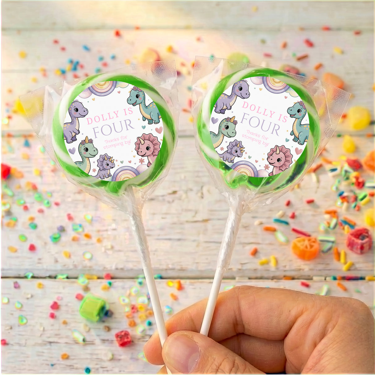 Green-rim dinosaur birthday lollipops with round “Dolly is Four” wrapper labels