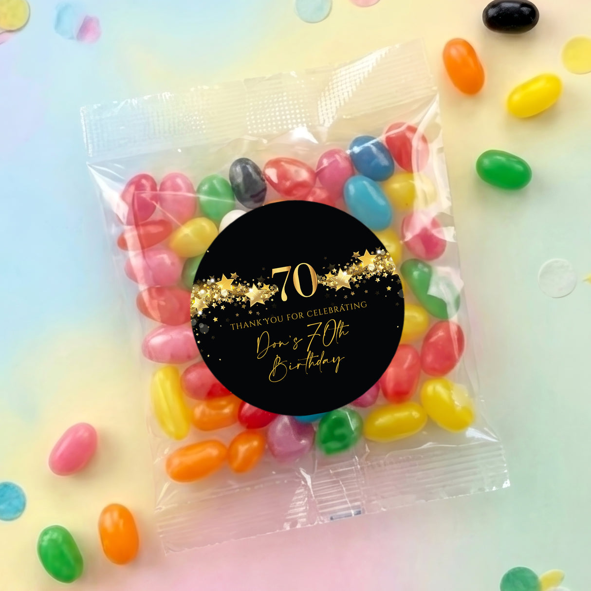 Clear jelly bean bag with black round '70th' design, gold stars and candy inside