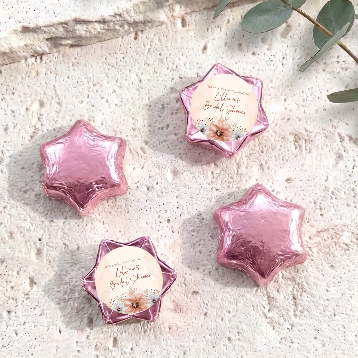 Pink foil-covered chocolate stars with floral bridal shower message labels