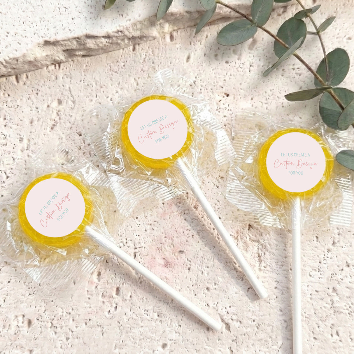 Mini lollipops with yellow lollipop tops, wrapped in clear plastic on white sticks.