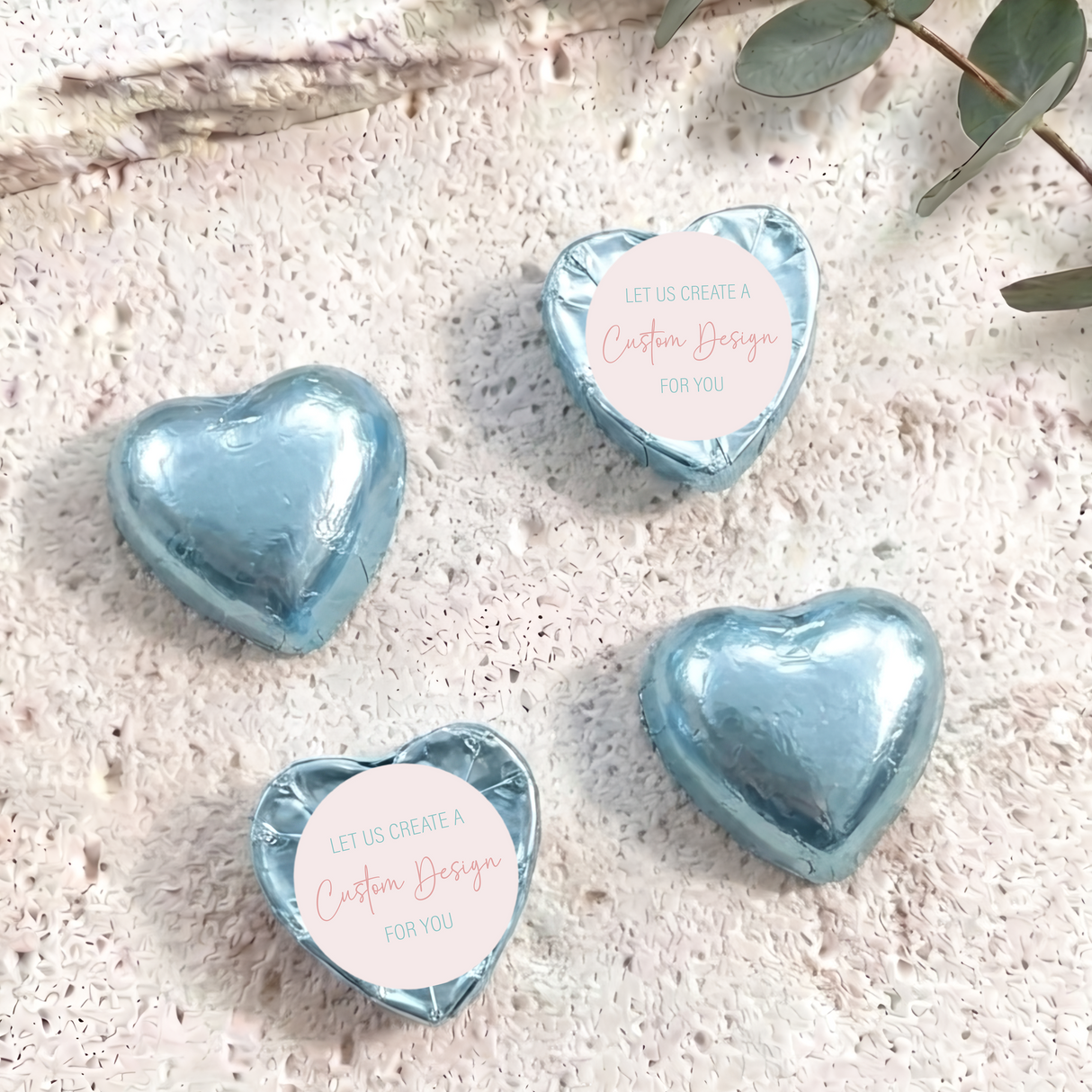 Light blue foil-covered heart chocolates with “Custom Design” card labels