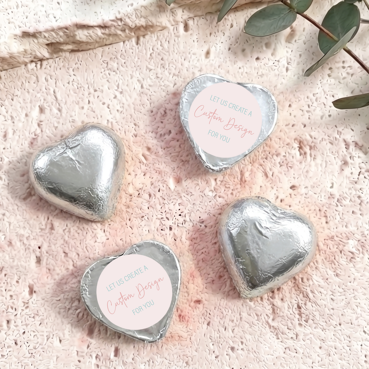 Silver foil-covered heart chocolates with “Custom Design” card labels