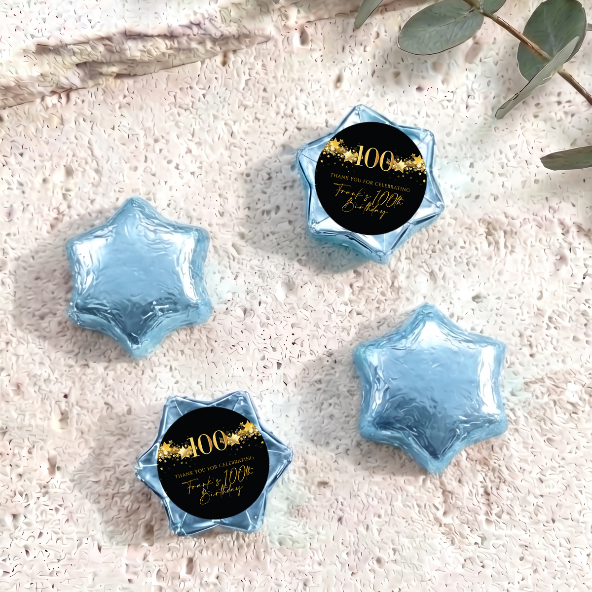 Blue foil-covered chocolate star sweets with a 100th birthday printed center