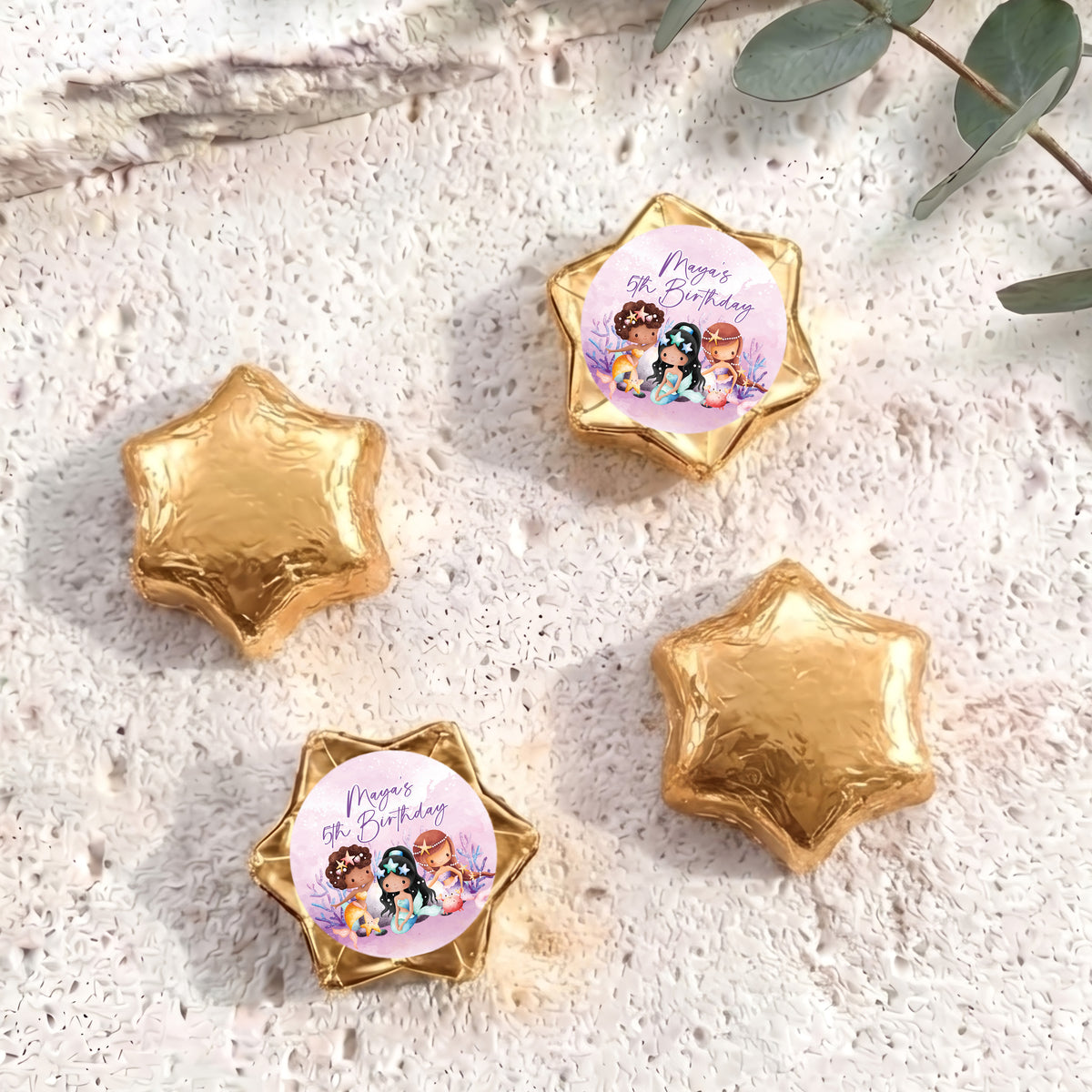 Gold foil-covered chocolate stars, with a colorful mermaid birthday label star