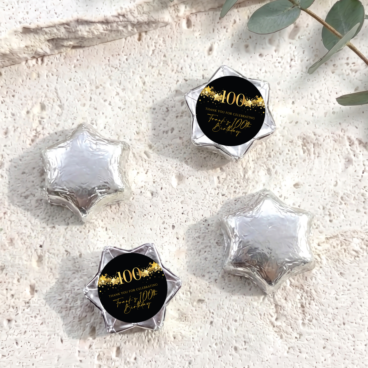 Silver foil-covered chocolate star sweets with a 100th birthday printed center