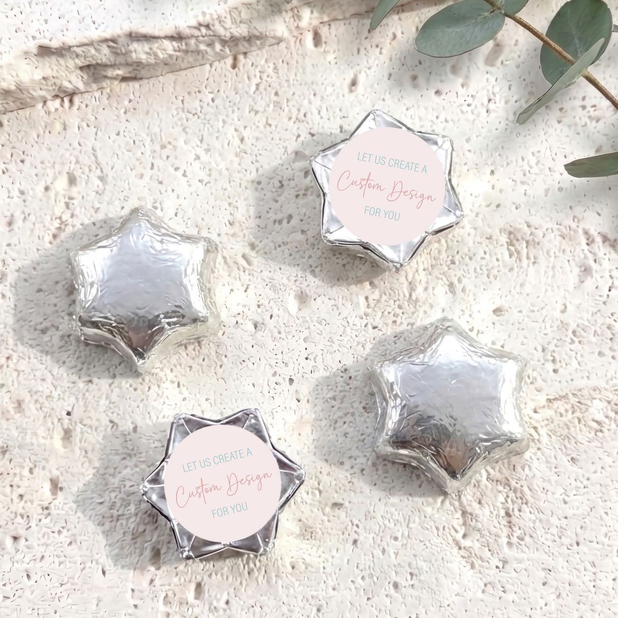 Silver foil-covered chocolate stars with circular “Custom Design for you” label