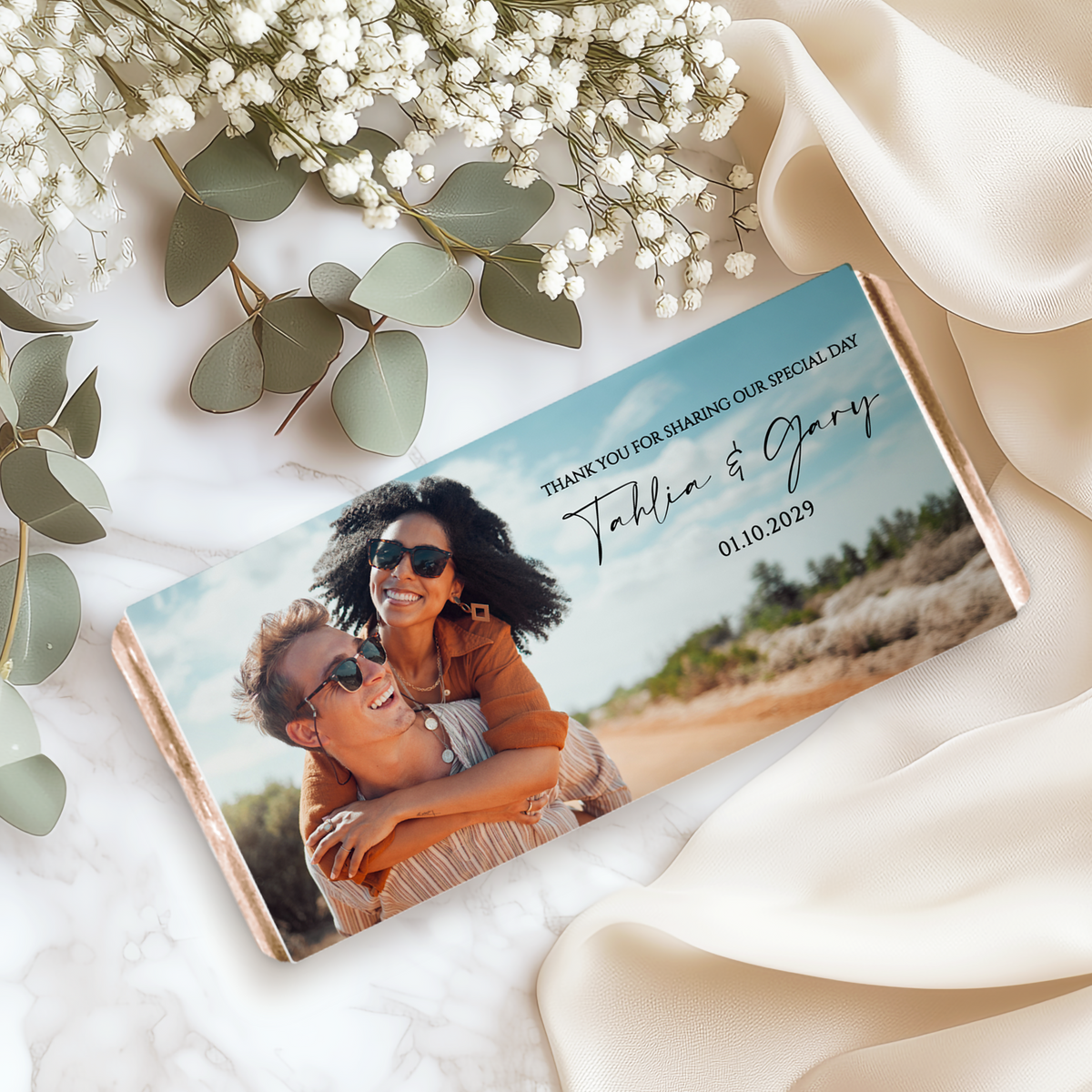 Personalised wedding chocolate bar with couple photo on teal wrapper, lying on fabric