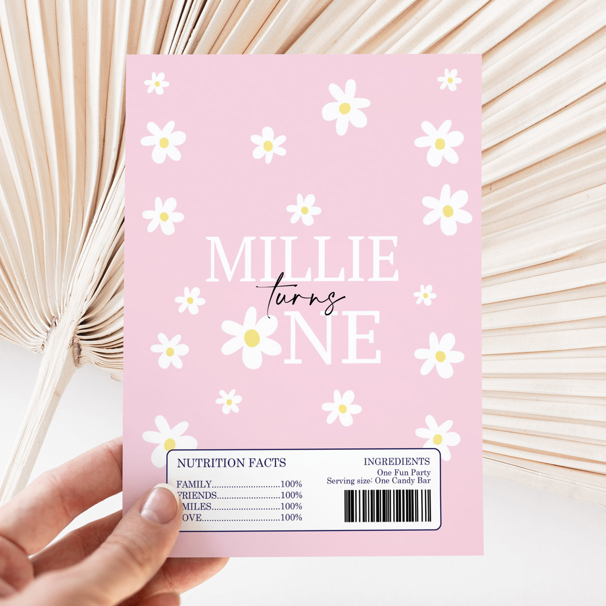 Pink chocolate bar wrapper with white daisy pattern and custom name text, barcode at bottom