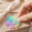 Round tie-dye birthday thank-you label with printed text, on a ribbon-tied box